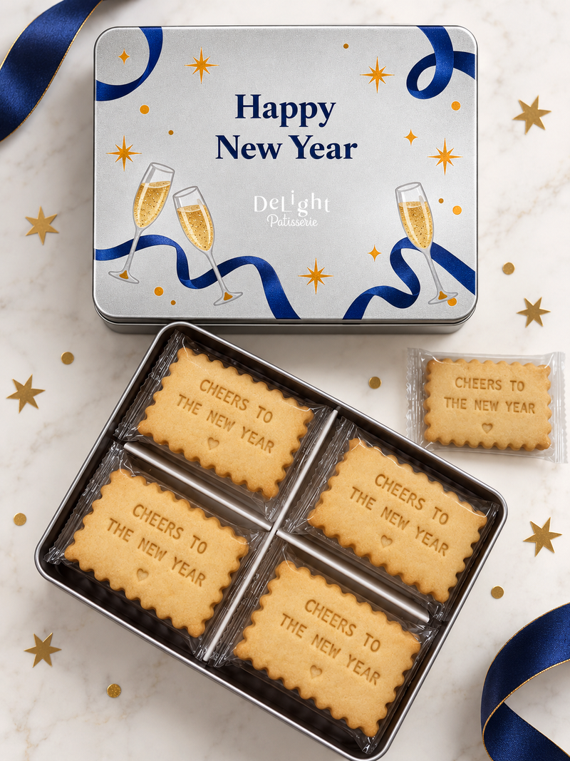 Happy New Year cookie tin featuring navy ribbons, golden stars, and champagne glasses, filled with shortbread cookies stamped “CHEERS TO THE NEW YEAR” and a heart - a thoughtful new year gift